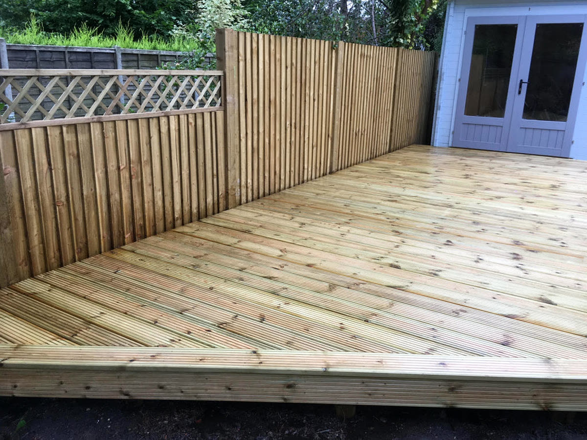 Newly built timber decking with closeboard fencing and a garden room