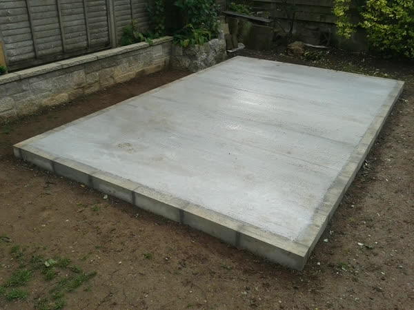 Newly laid concrete shed base with a block edge in a back garden