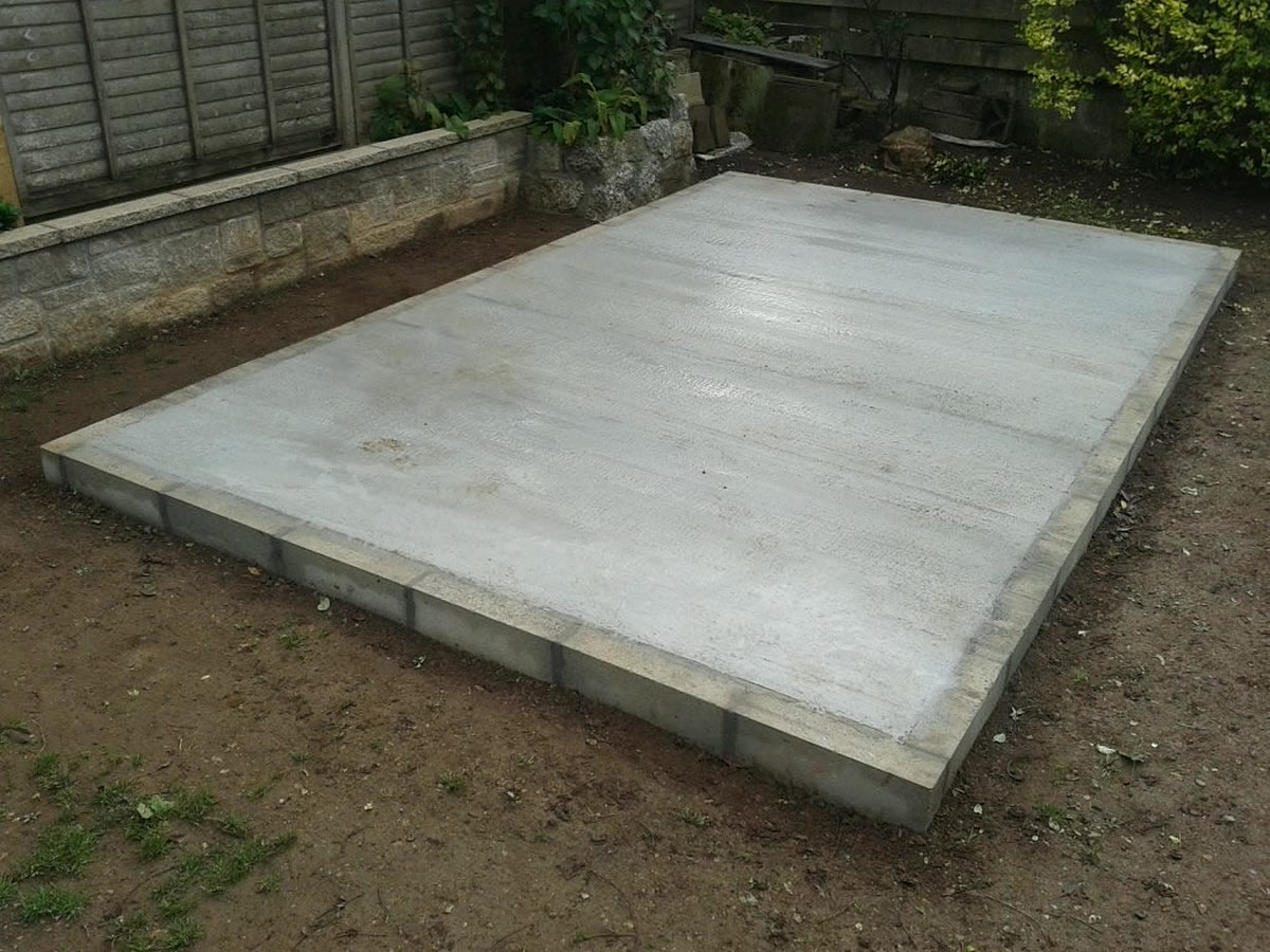 Newly laid concrete shed base with a block edge in a back garden