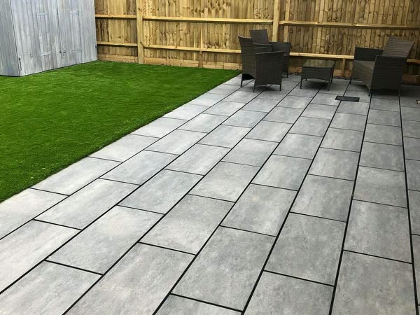 New porcelain patio laid beside artificial grass and closeboard fencing